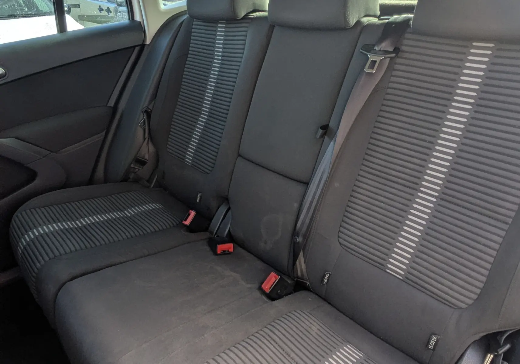 Vue intérieure de la banquette arrière noire du Volkswagen Tiguan 2010, avec appuie-têtes et ceintures visibles.