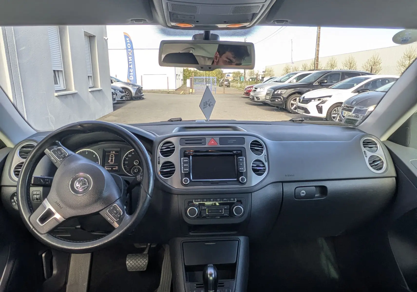 Vue intérieure avant du Volkswagen Tiguan 2010 avec tableau de bord noir et sièges tissu rayés gris.