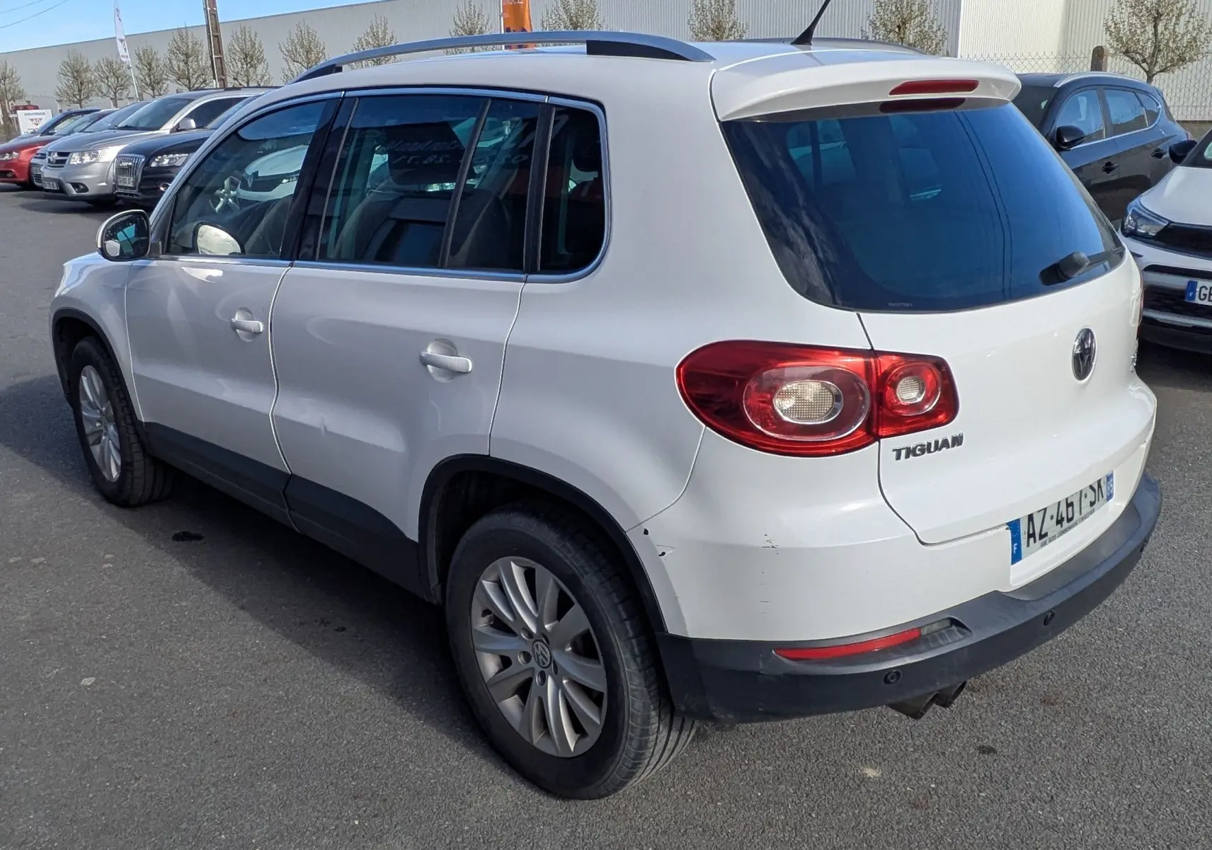 Volkswagen Tiguan blanc vu en 3/4 arrière droit, avec jantes alu et toit ouvrant électrique visible.