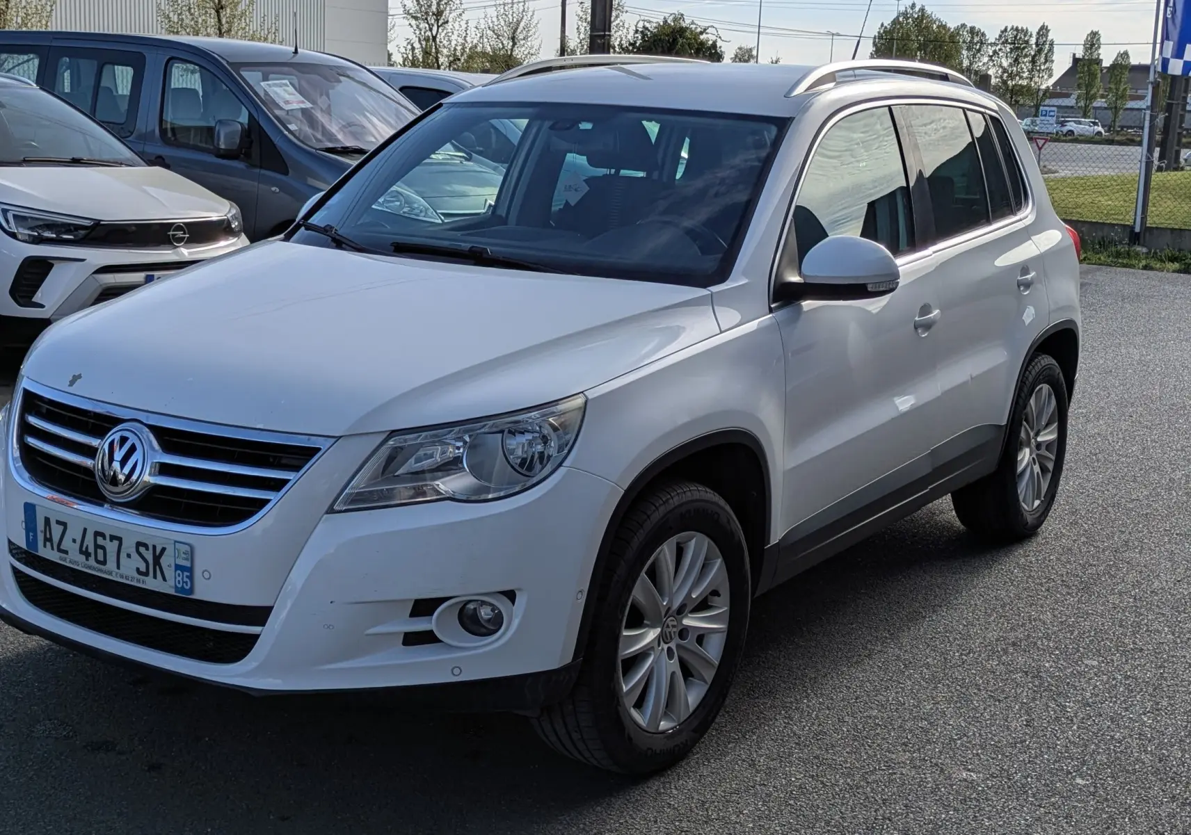 Volkswagen Tiguan blanc vu en 3/4 avant droit, avec jantes alu et toit ouvrant électrique visible.