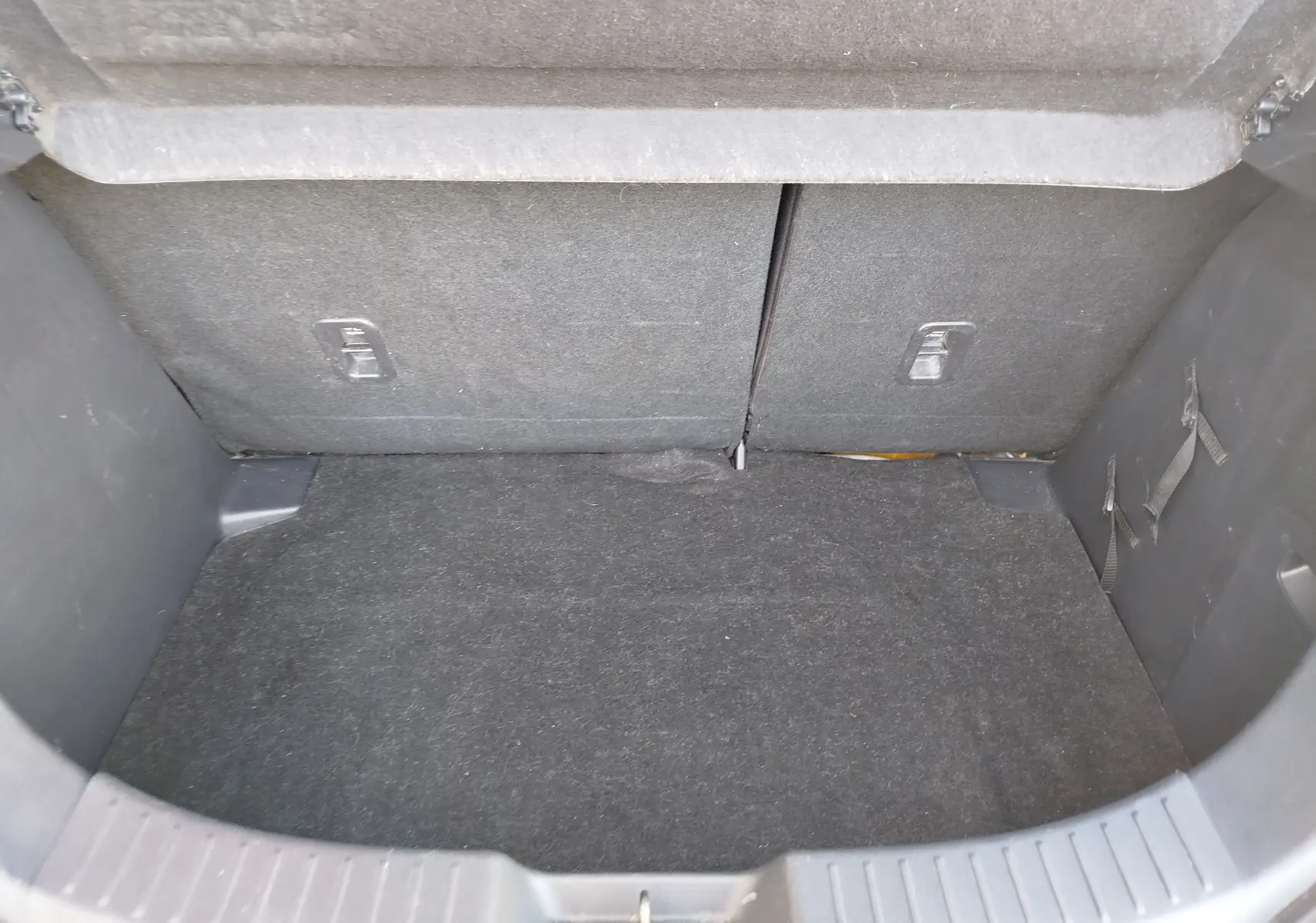 Coffre vide vu de l'arrière d'une Mazda2 2018 blanche, avec revêtement intérieur en tissu gris foncé.