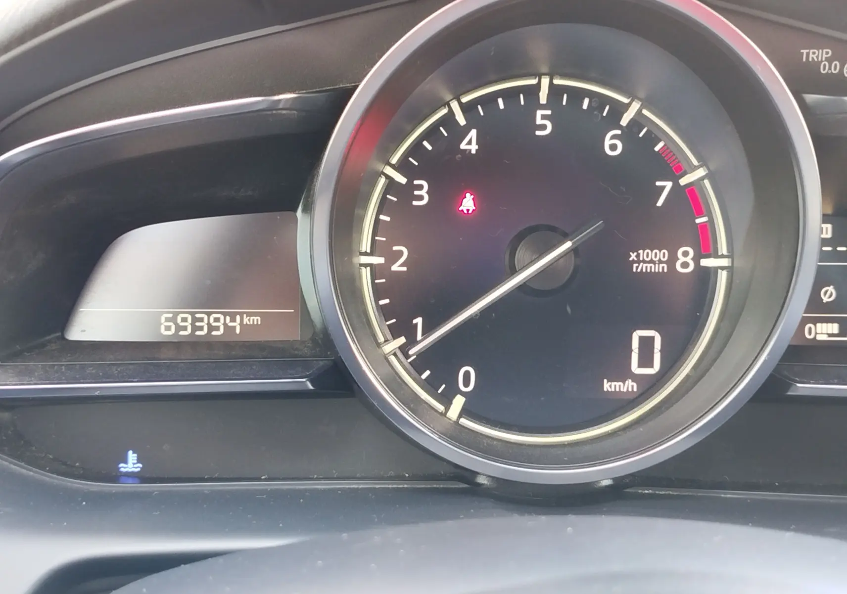 Vue rapprochée du compte-tours et odomètre affichant 69394 km sur le tableau de bord d'une Mazda2.