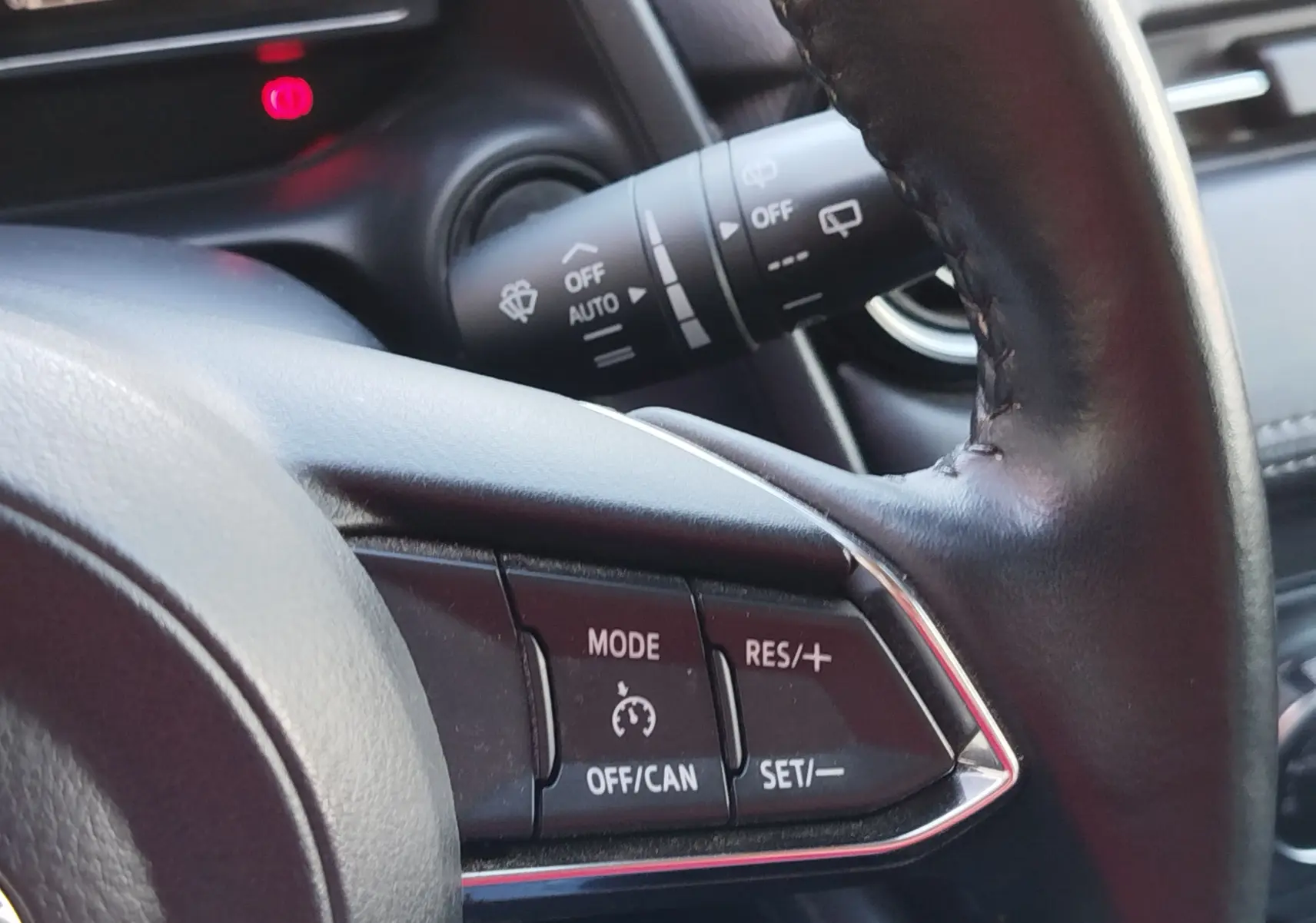 Gros plan sur le volant noir de la Mazda2 2018, montrant les commandes du régulateur de vitesse côté gauche.