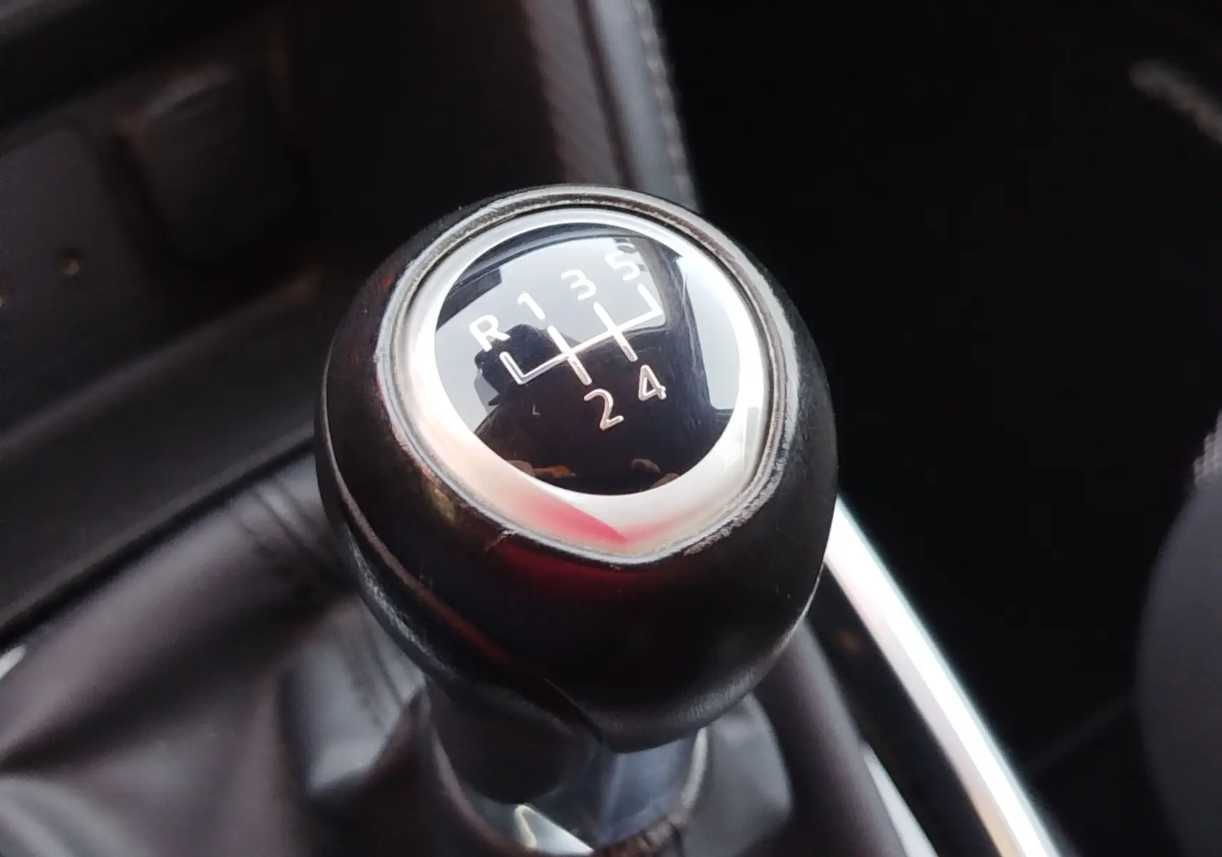 Gros plan sur le levier de vitesses manuel noir de la Mazda2 2018, montrant la grille des 5 rapports et la marche arrière.