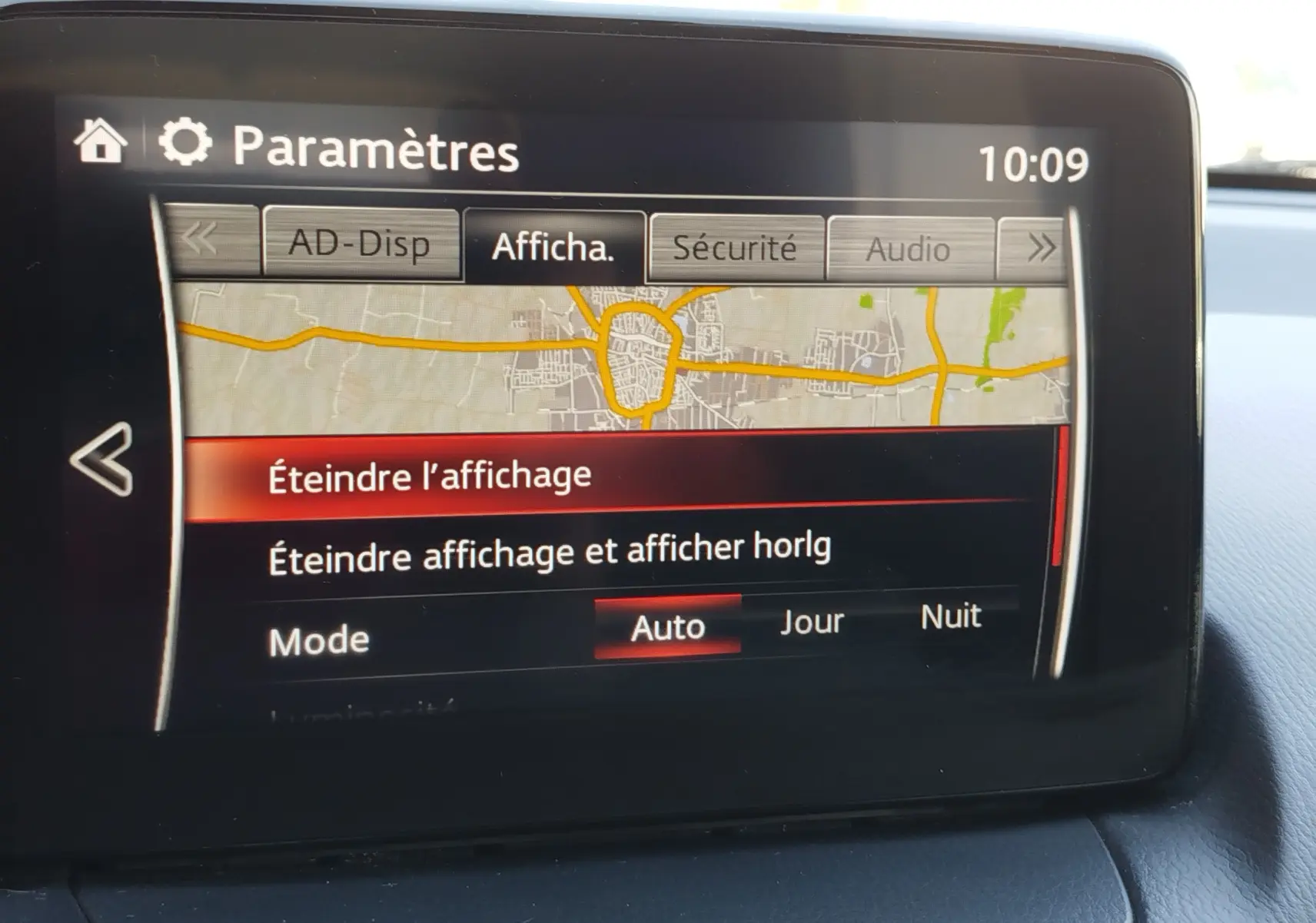 Écran central de la Mazda2 2018 affichant le menu des paramètres avec options d'affichage et carte routière partielle.