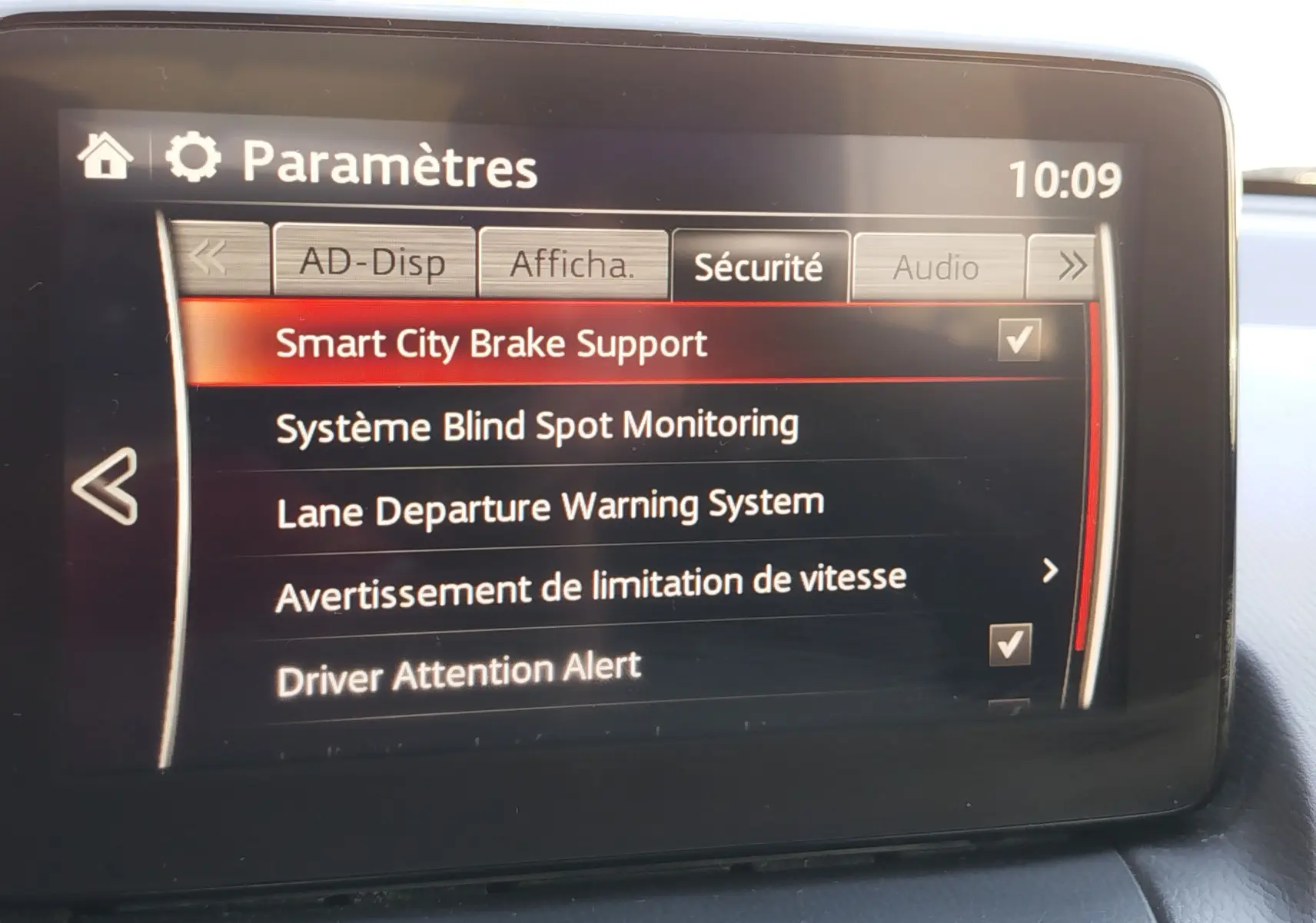 Écran central du tableau de bord de la Mazda2 2018 affichant les paramètres de sécurité du système d'aide à la conduite.