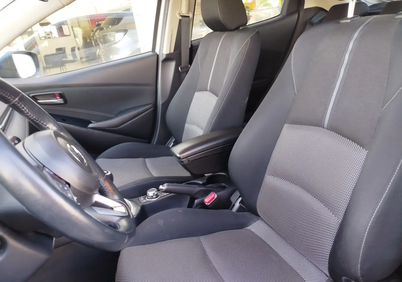 Vue intérieure côté conducteur de la Mazda2 2018 avec sièges tissu gris et volant cuir noir.