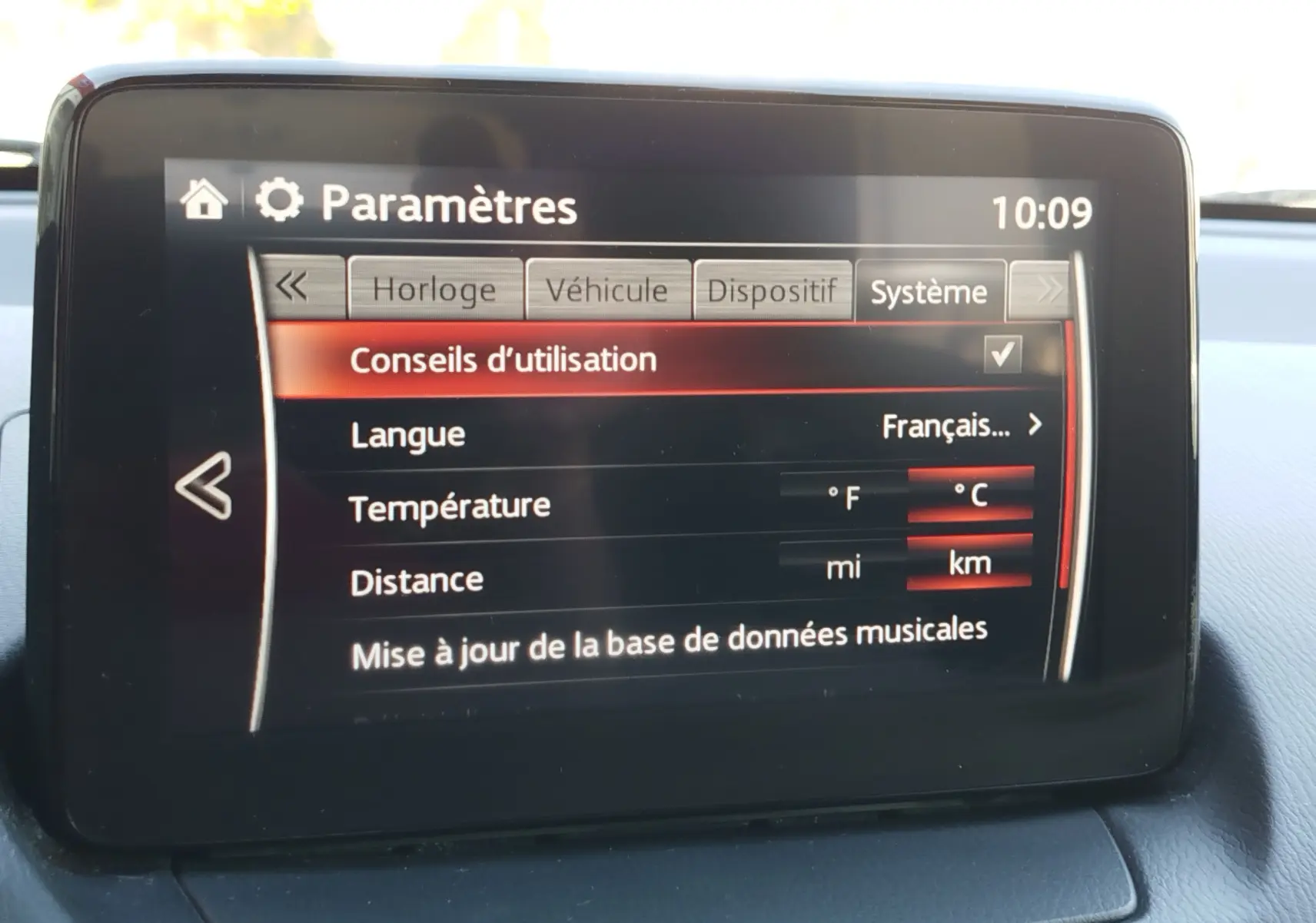 Écran central de la Mazda2 montrant le menu des paramètres système avec options de langue, température et distance.