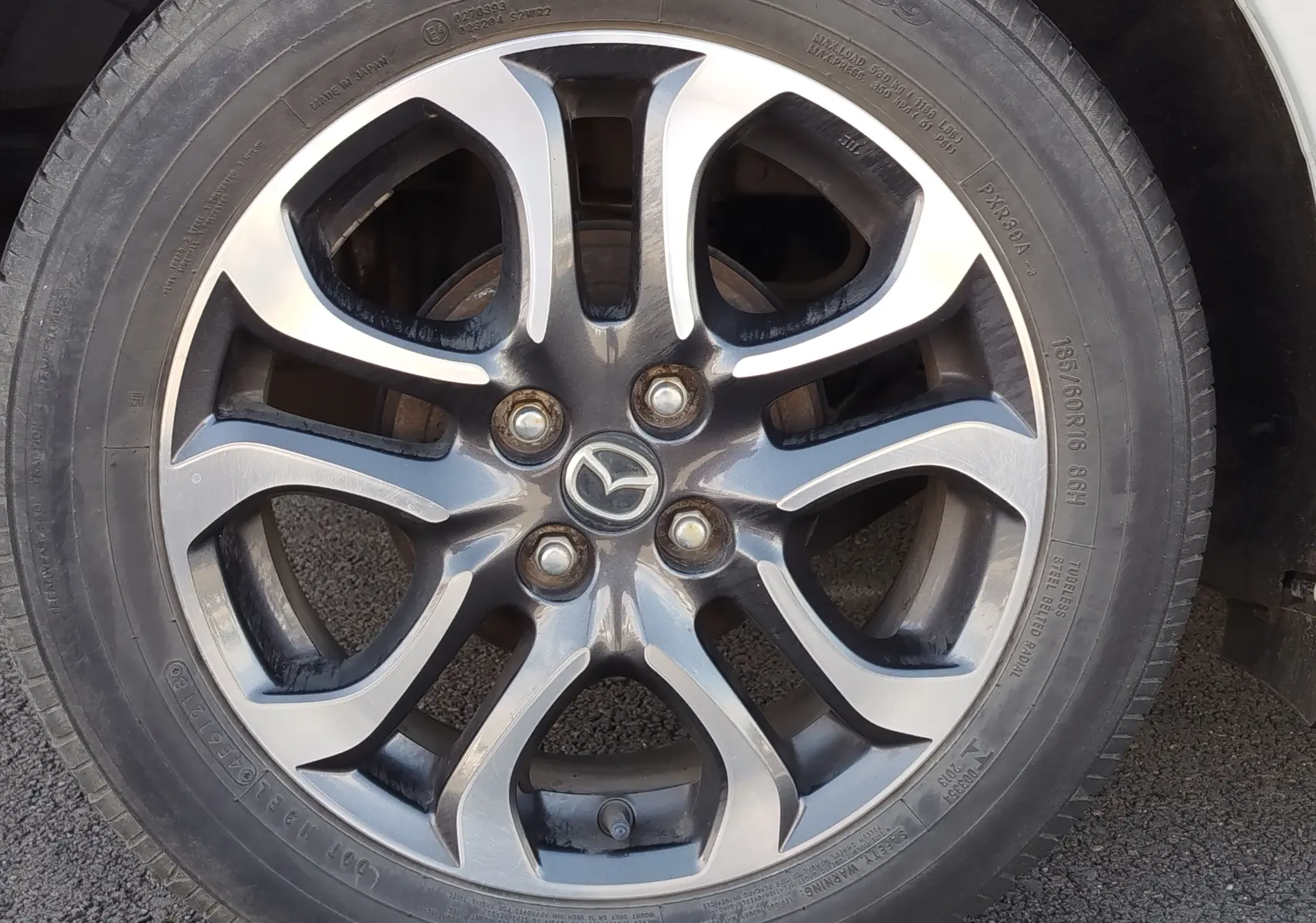 Gros plan sur la jante alliage bicolore de la Mazda2 Snowflake White Pearl Mica de 2018, avec logo Mazda central.