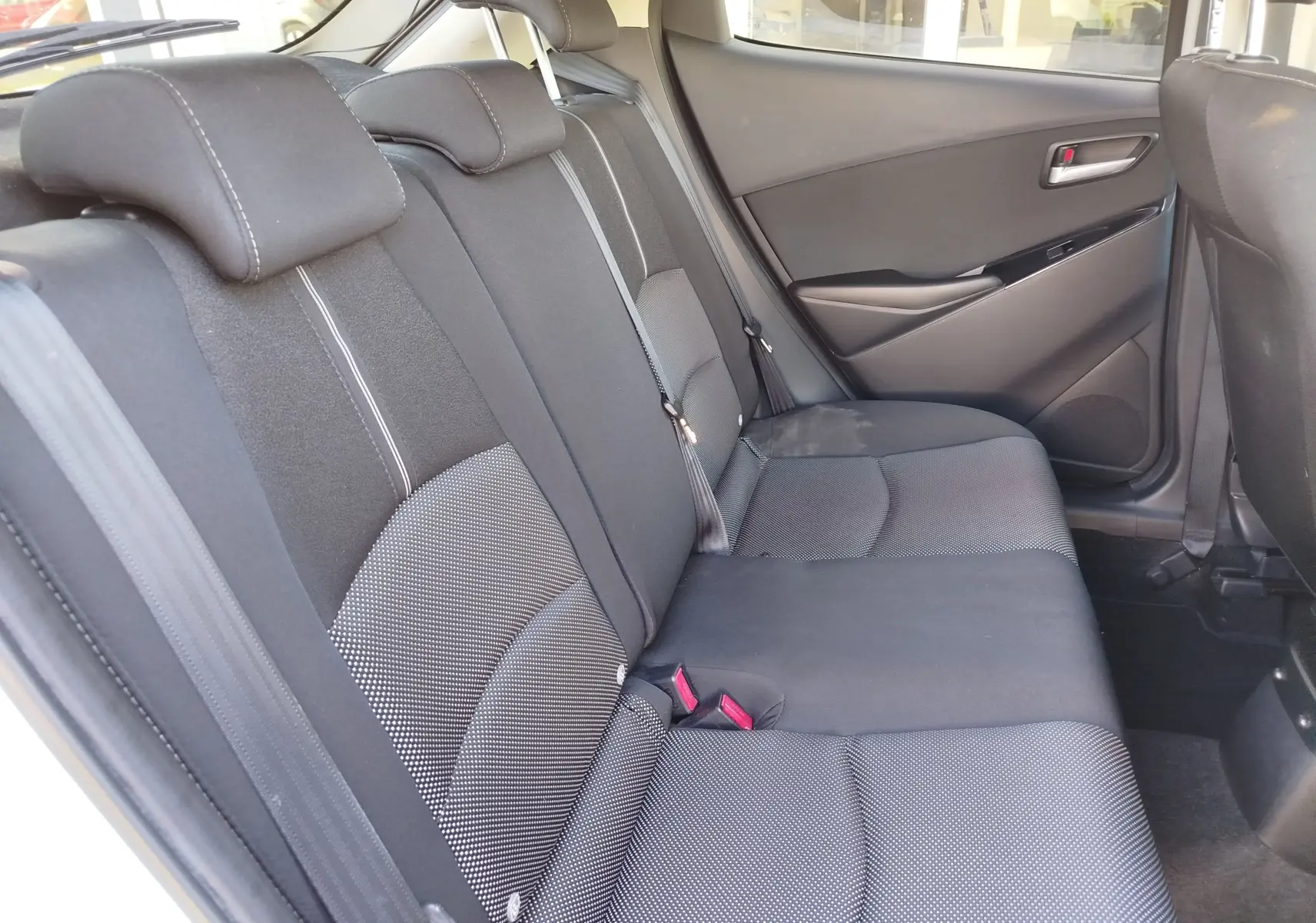 Vue intérieure côté droit des sièges arrière en tissu gris foncé de la Mazda2 2018 Snowflake White Pearl Mica.