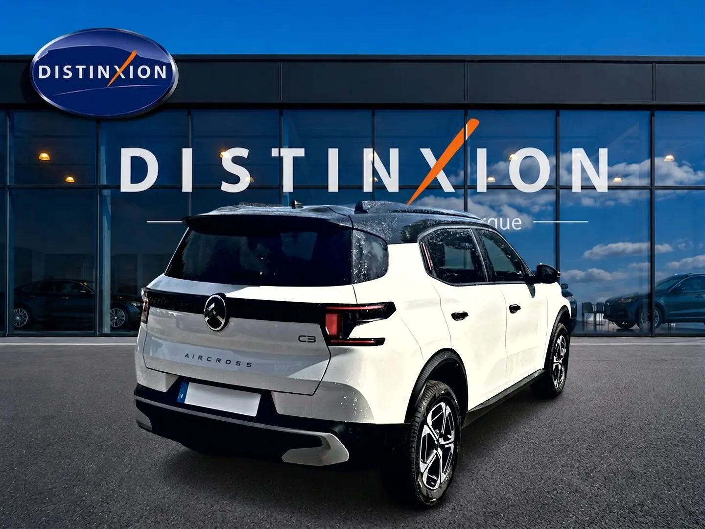 Vue 3/4 arrière droite d'un Citroën C3 Aircross blanc avec toit noir, garé devant une vitrine Distinxion.