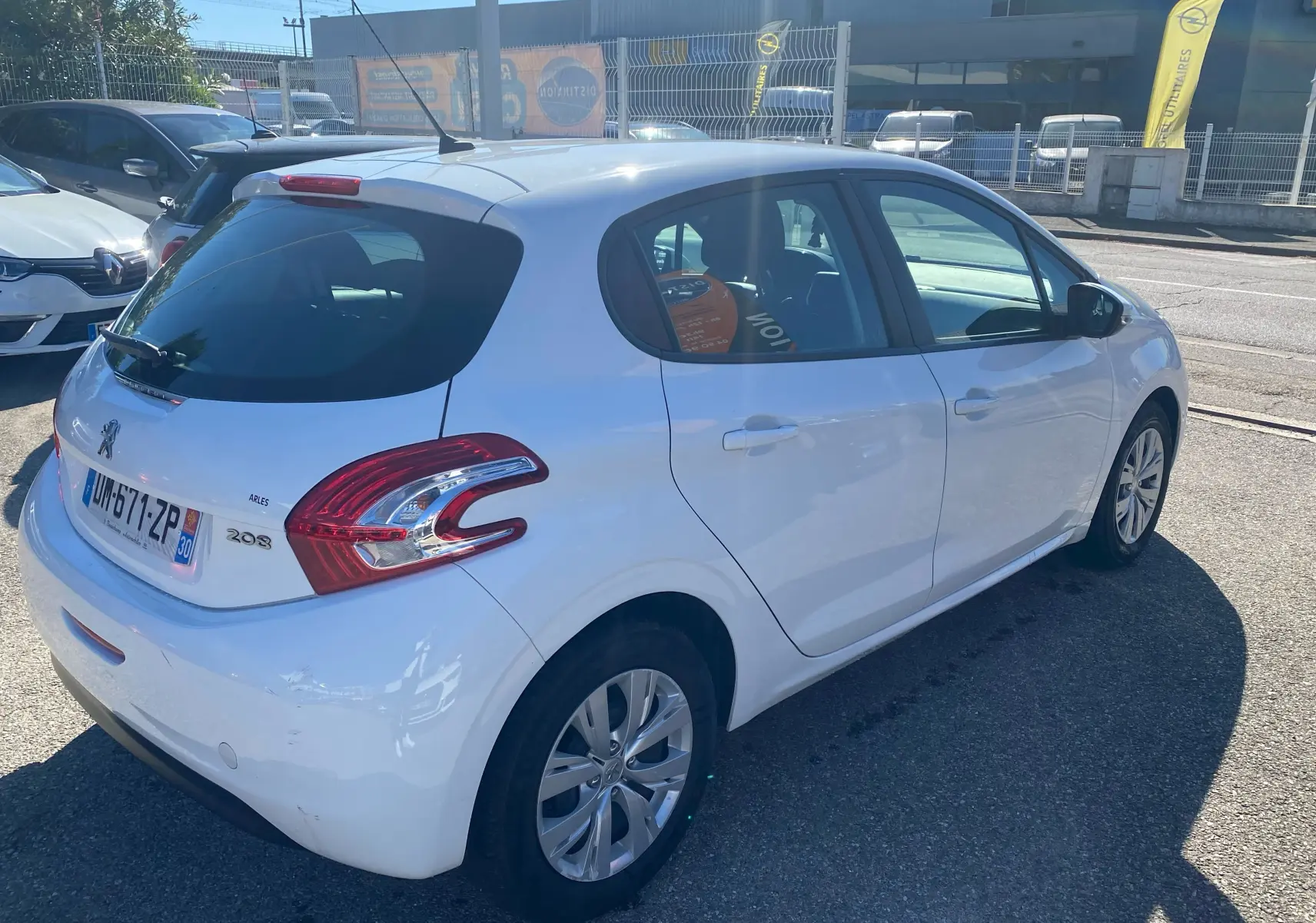 Peugeot 208 blanche vue en 3/4 arrière côté droit, avec feux arrière distinctifs et cinq portes visibles.