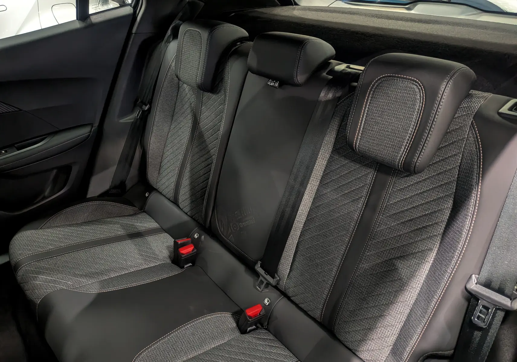 Vue intérieure sur les sièges arrière en tissu et cuir noir avec surpiqûres contrastées du Peugeot 2008 Hybrid 145 e-DCS6.