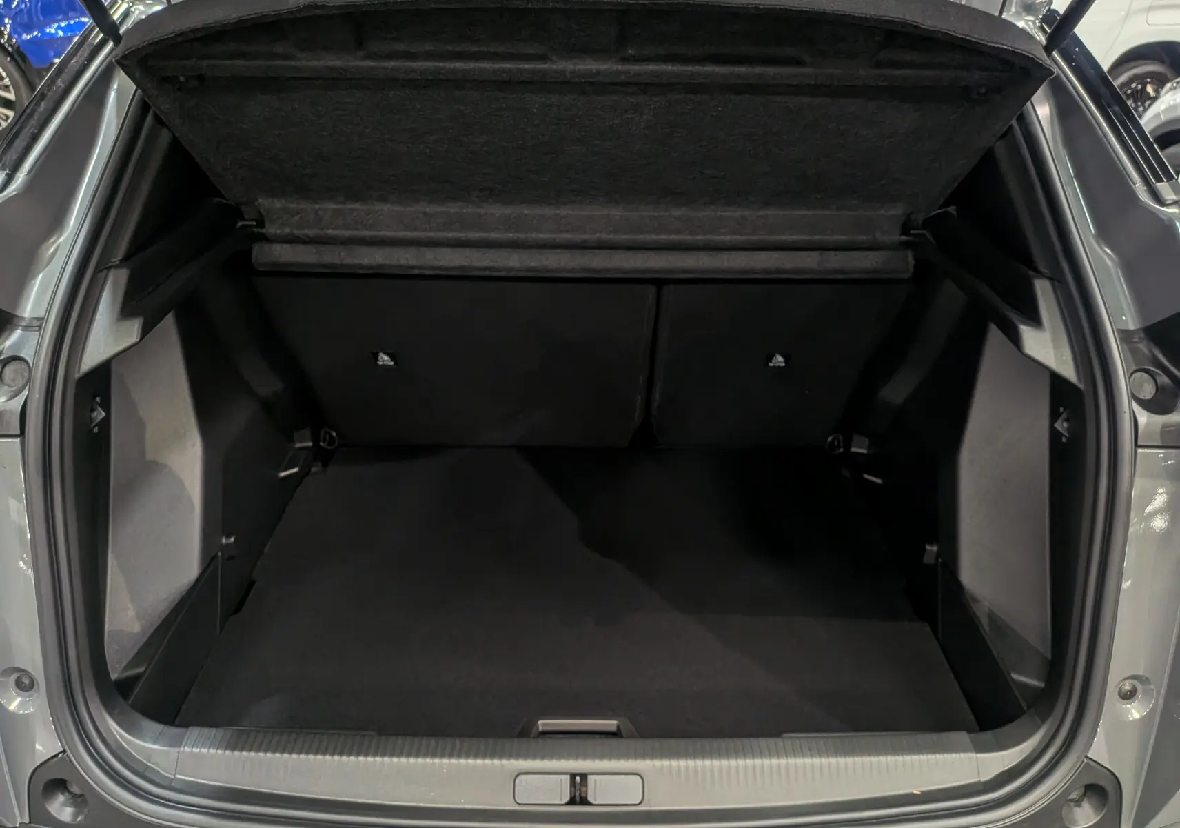 Coffre ouvert d'un Peugeot 2008 Hybrid 145 e-DCS6 Allure gris Sélénium, vue arrière montrant l'espace de chargement vide.
