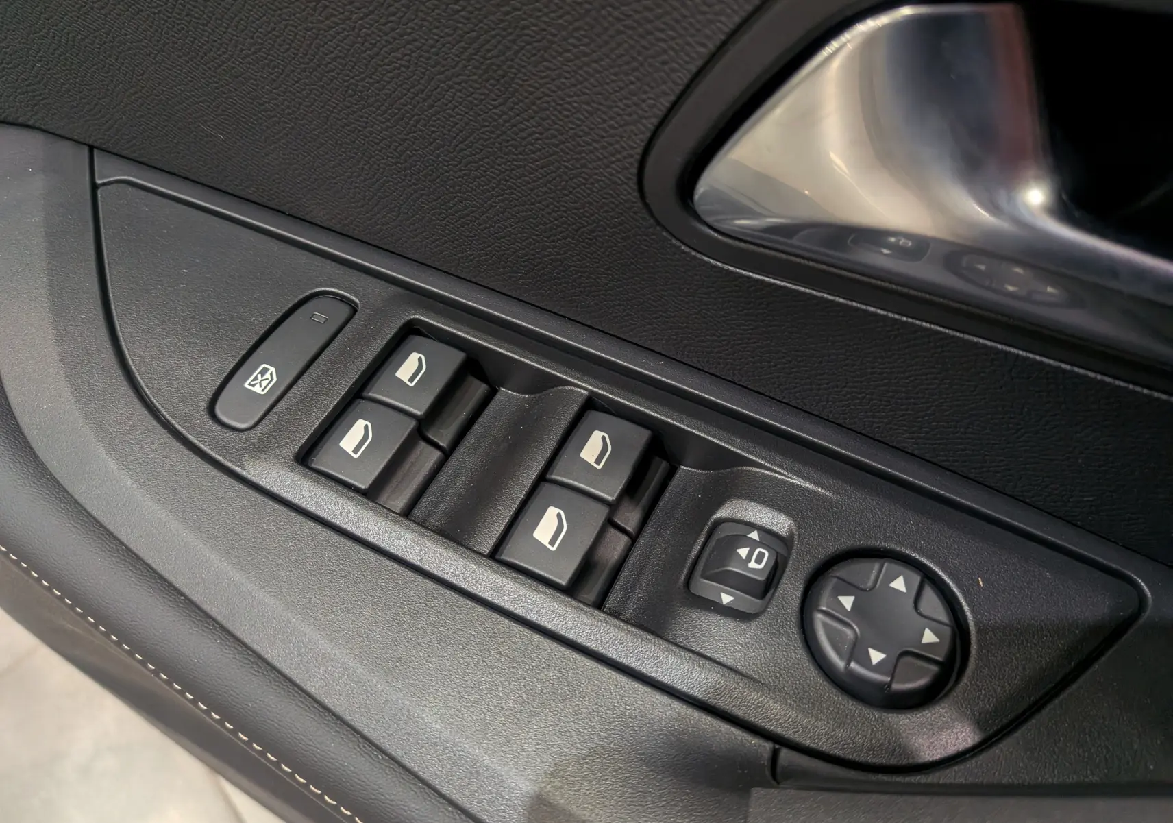 Panneau de commandes des vitres et rétroviseurs côté conducteur d'un Peugeot 2008 Hybrid 145 gris Sélénium, intérieur noir.