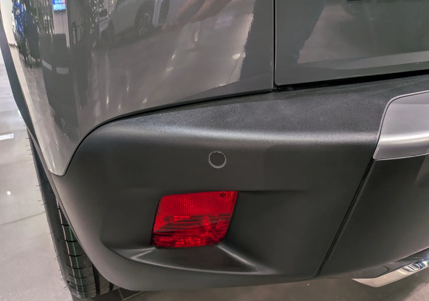 Gros plan sur le feu arrière droit et le pare-chocs noir du Peugeot 2008 Hybrid 145 gris Sélénium, version 2025.