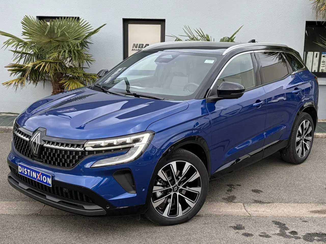 Renault Austral E-Tech bleu Iron avec toit noir panoramique, vue 3/4 avant mettant en valeur les jantes 19 pouces.