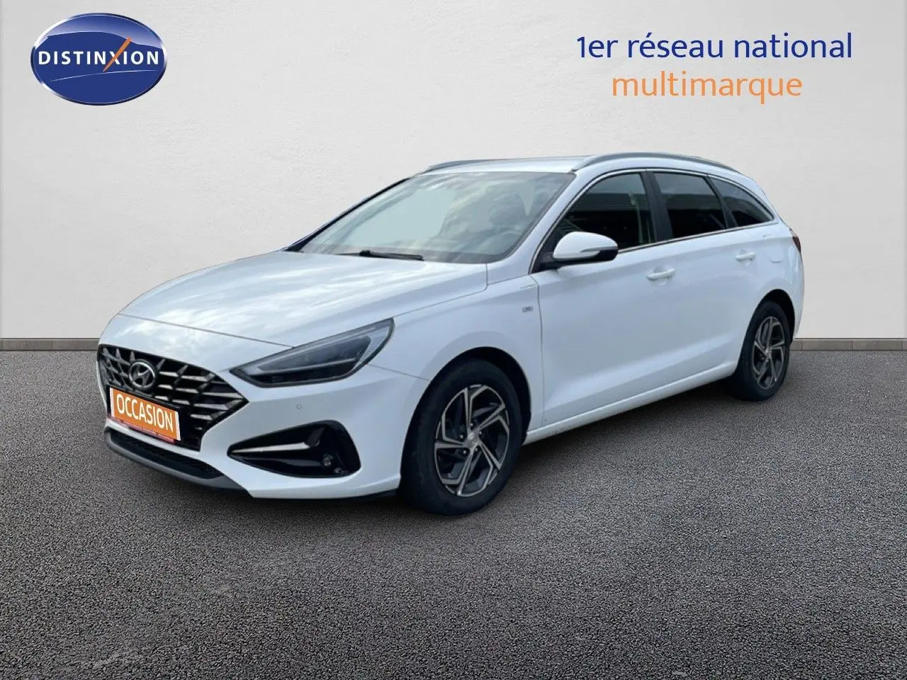 Vue 3/4 avant droite d'une Hyundai i30 SW 2022 en blanc Atlas avec jantes alliage et calandre noire distinctive.