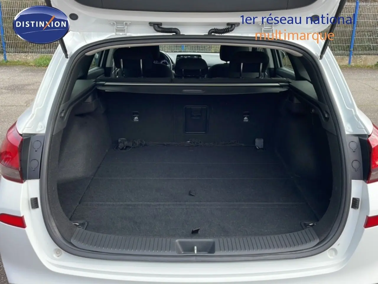 Vue arrière du coffre ouvert d'une Hyundai i30 SW blanche, montrant un espace de chargement vide et spacieux.