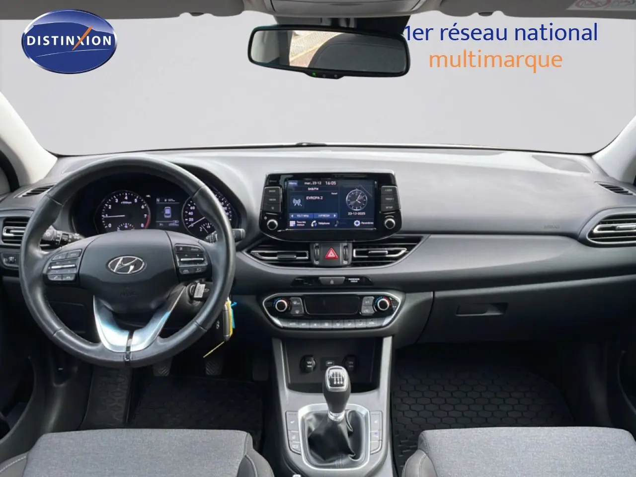 Vue intérieure avant de la Hyundai i30 SW 2022, tableau de bord noir avec volant cuir et levier de vitesse manuel.