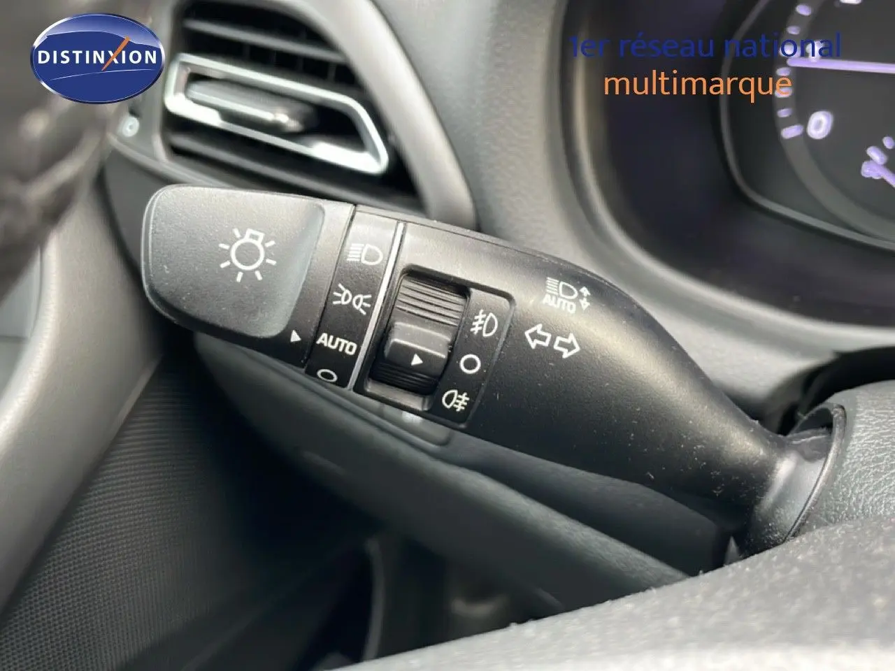 Gros plan sur la commande des feux et clignotants côté gauche du tableau de bord d'une Hyundai i30 SW blanche.