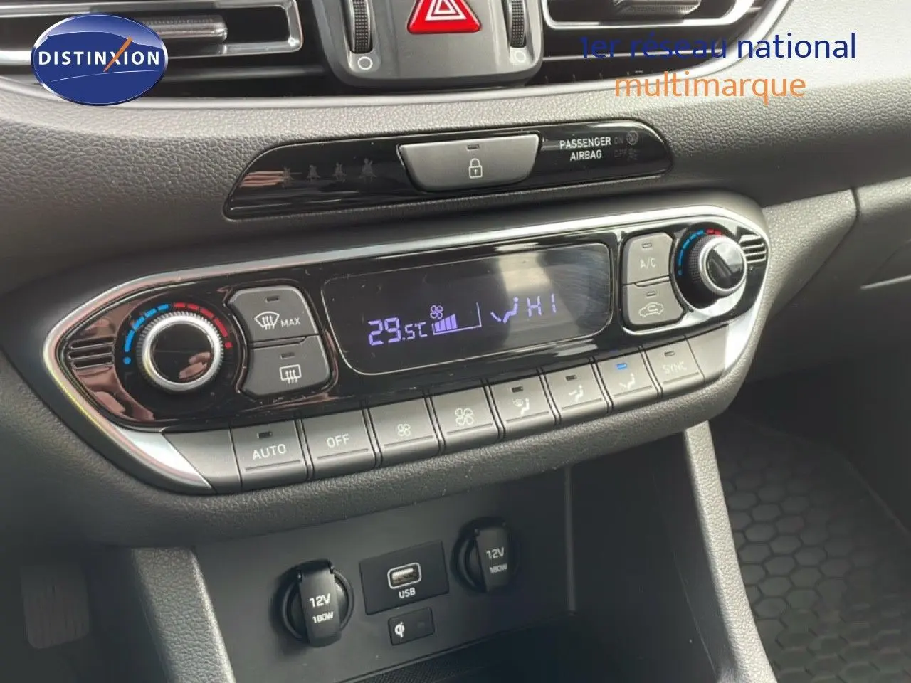 Vue rapprochée du tableau de bord de la Hyundai i30 SW blanc Atlas, montrant la console de climatisation digitale et les prises USB et 12V.