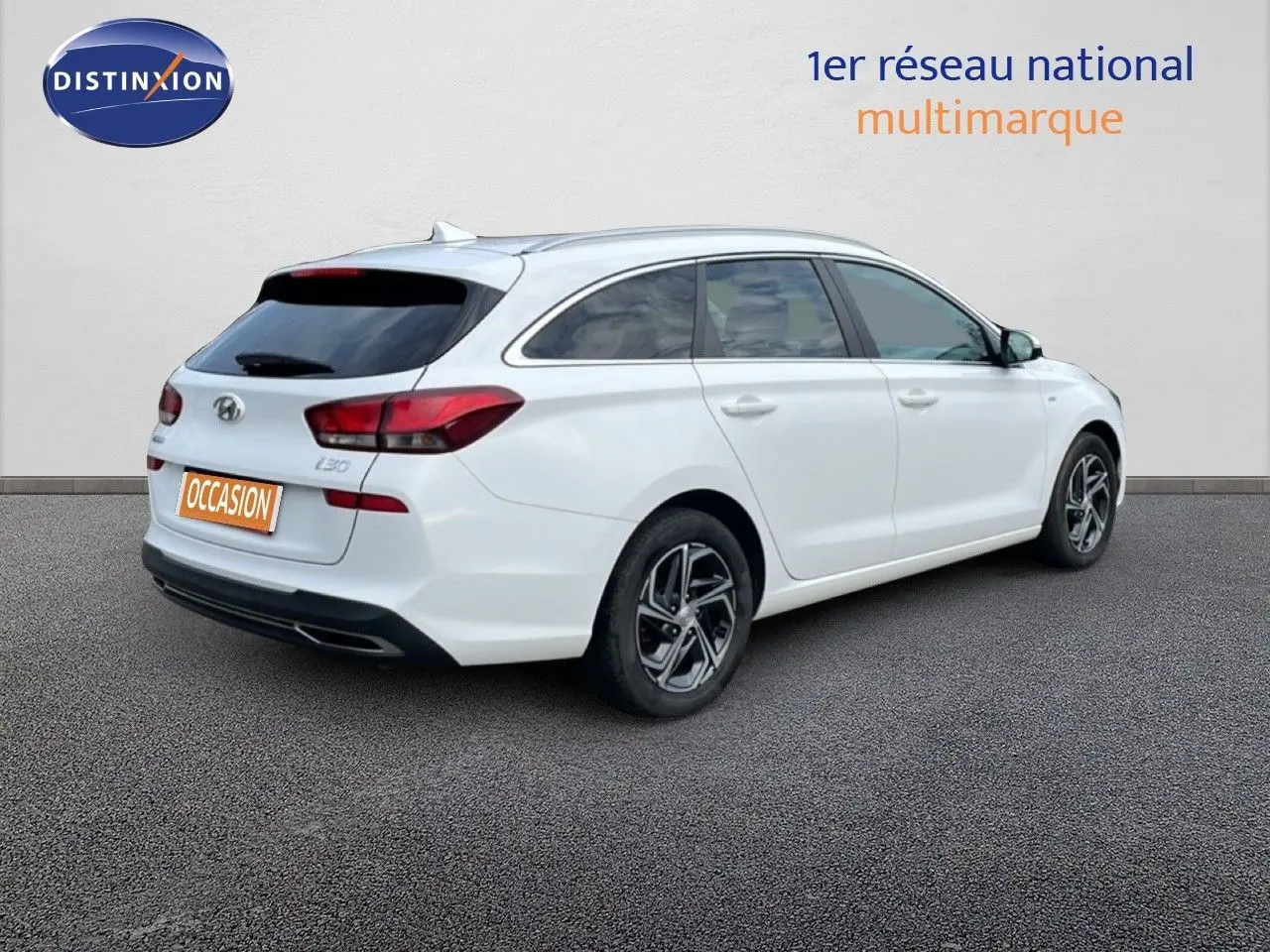 Vue 3/4 arrière droite d'une Hyundai i30 SW blanche Atlas, break compact avec vitres teintées et jantes alliage.