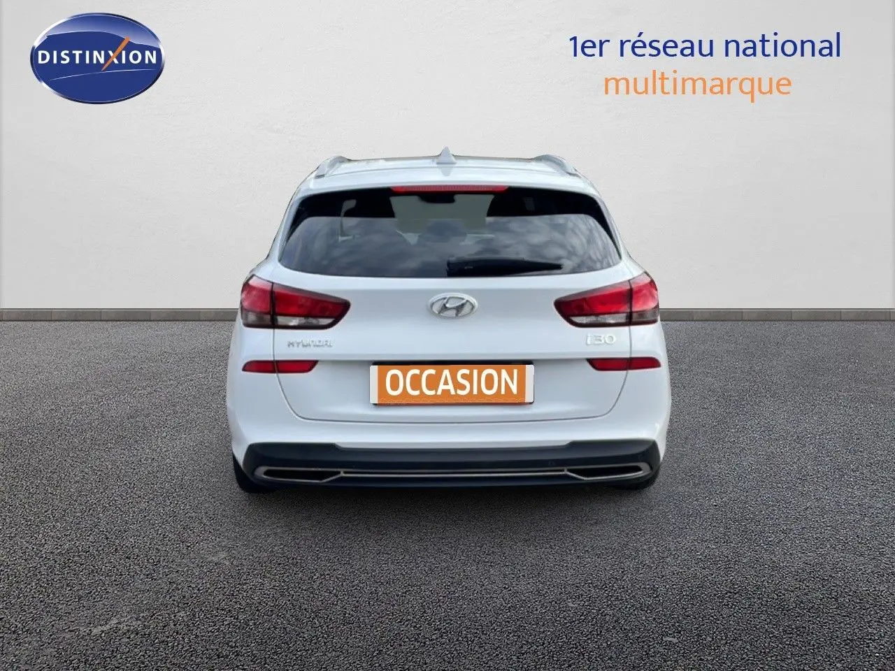Vue arrière d'une Hyundai i30 SW blanche Atlas de 2022 avec feux arrière rouges et plaque "OCCASION" visible.
