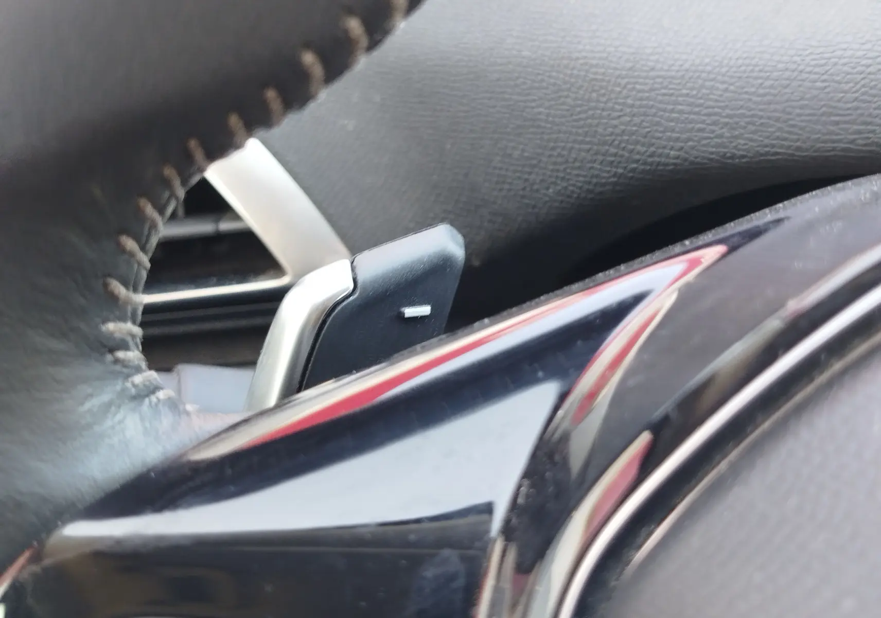 Gros plan sur la palette de changement de vitesse derrière le volant en cuir noir du Peugeot 3008 hybride.
