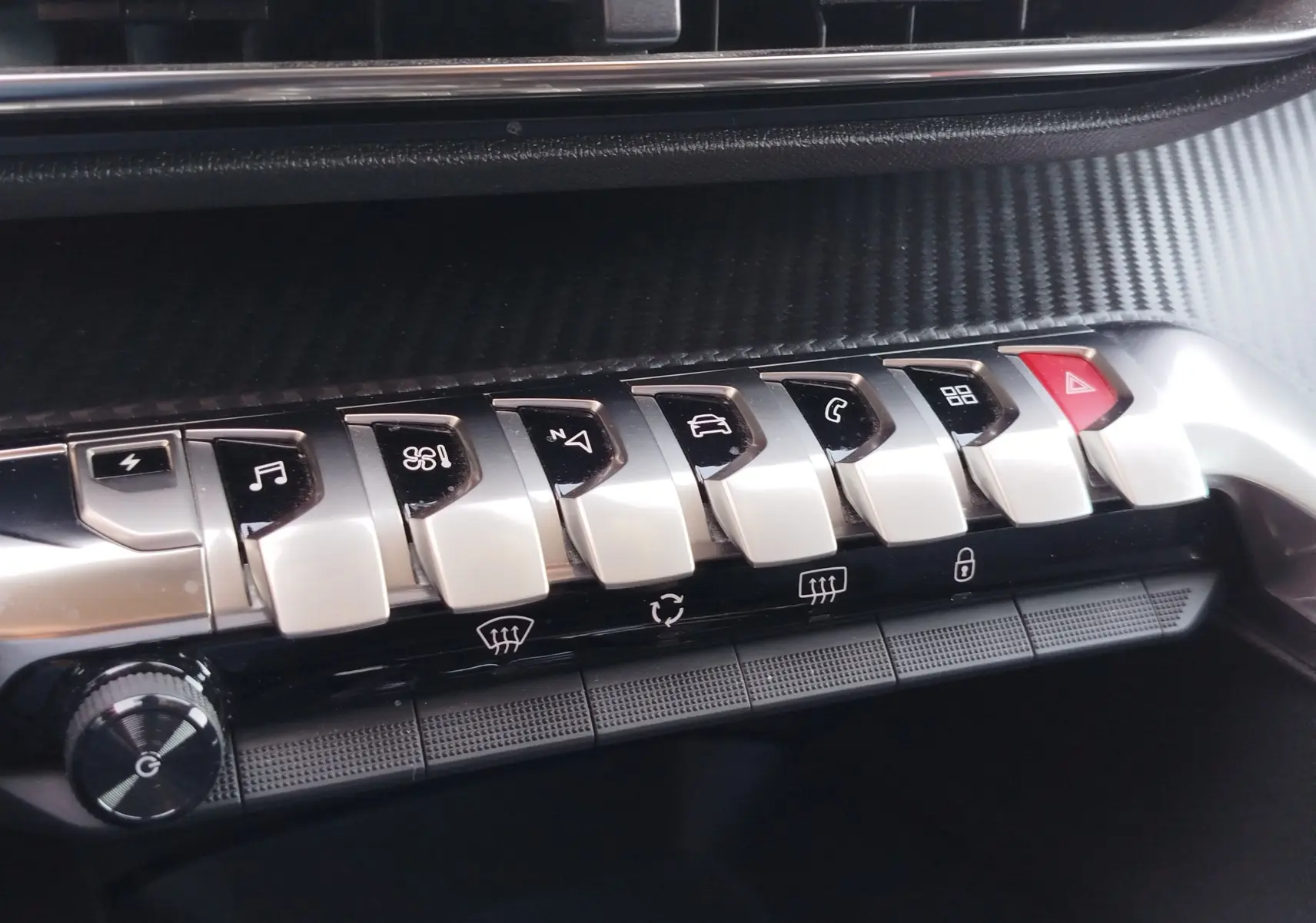 Gros plan sur la rangée de boutons argentés et noirs du tableau de bord du Peugeot 3008 bleu, avec bouton rouge d’alerte visible.