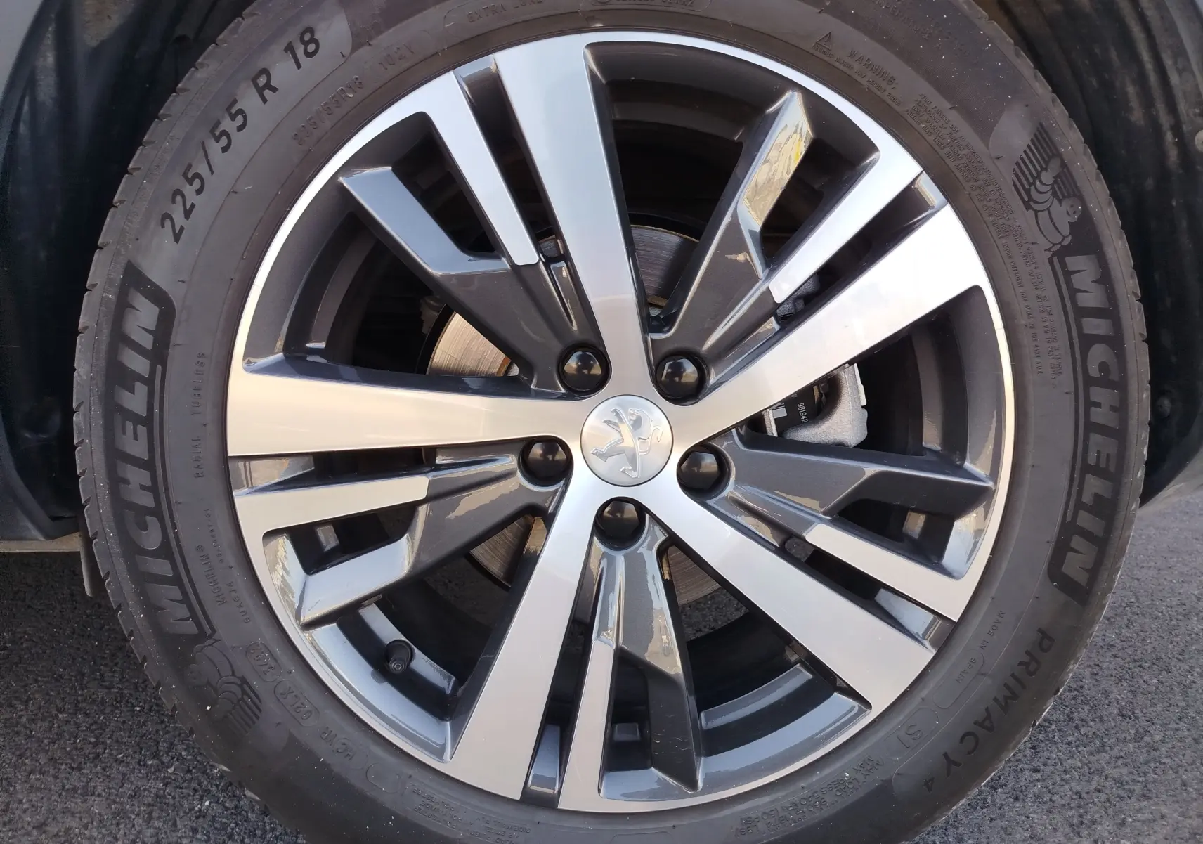 Gros plan sur la jante alliage bicolore et pneu Michelin d'un Peugeot 3008 Hybrid 225ch Allure 2022 bleu Célèbes.