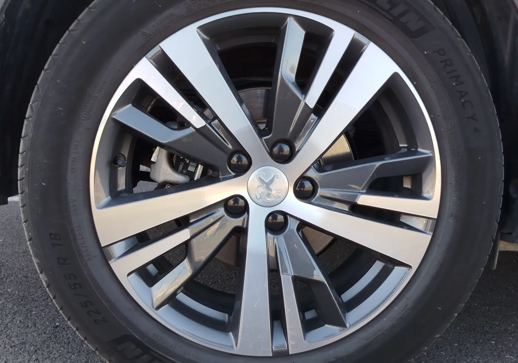 Gros plan sur la jante alliage bicolore argent et gris du Peugeot 3008 Hybrid 225ch, avec logo lion au centre.