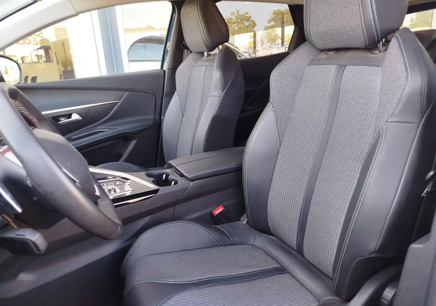 Vue intérieure côté conducteur du Peugeot 3008 Hybrid 225ch Allure 2022, sièges tissu et cuir gris avec surpiqûres bleues.