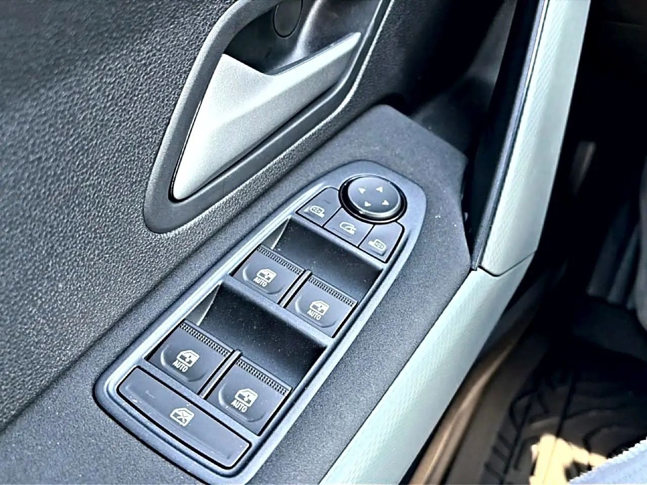Gros plan sur les commandes des vitres électriques côté gauche d'une Dacia Bigster blanche, intérieur noir et gris.