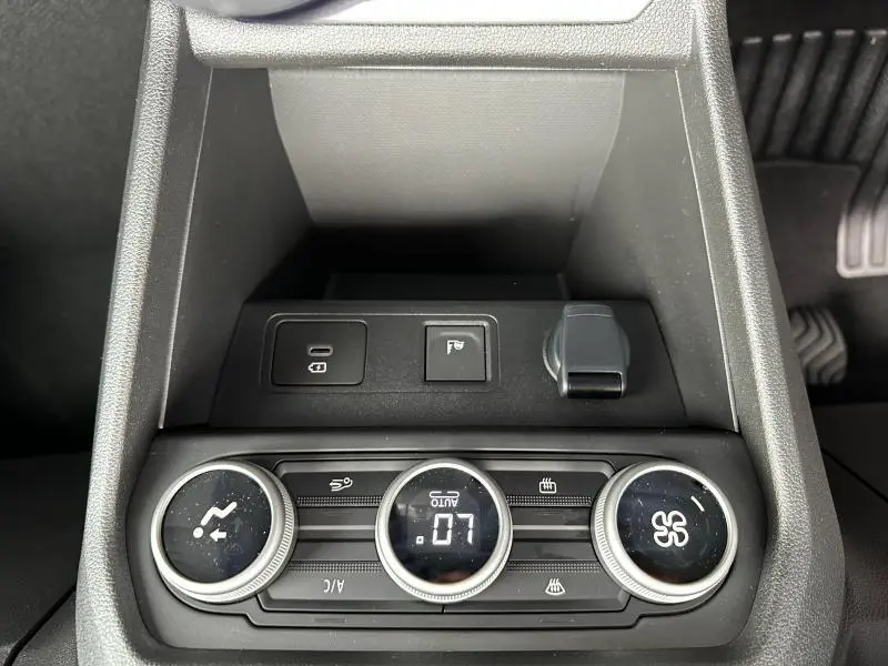 Vue rapprochée de la console centrale noire du Dacia Jogger 2024 avec commandes de climatisation et prise USB.