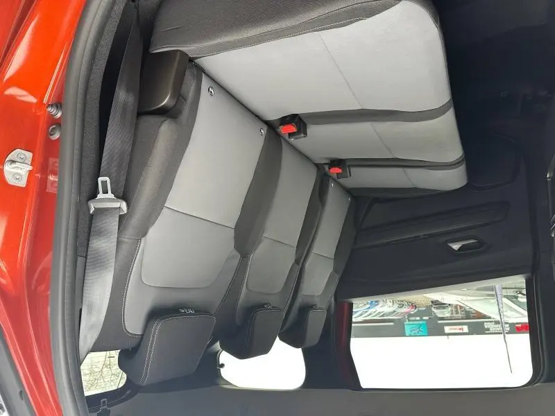 Vue intérieure du siège arrière gris clair et noir du Dacia Jogger 2024, avec ceinture de sécurité et porte ouvert côté gauche.