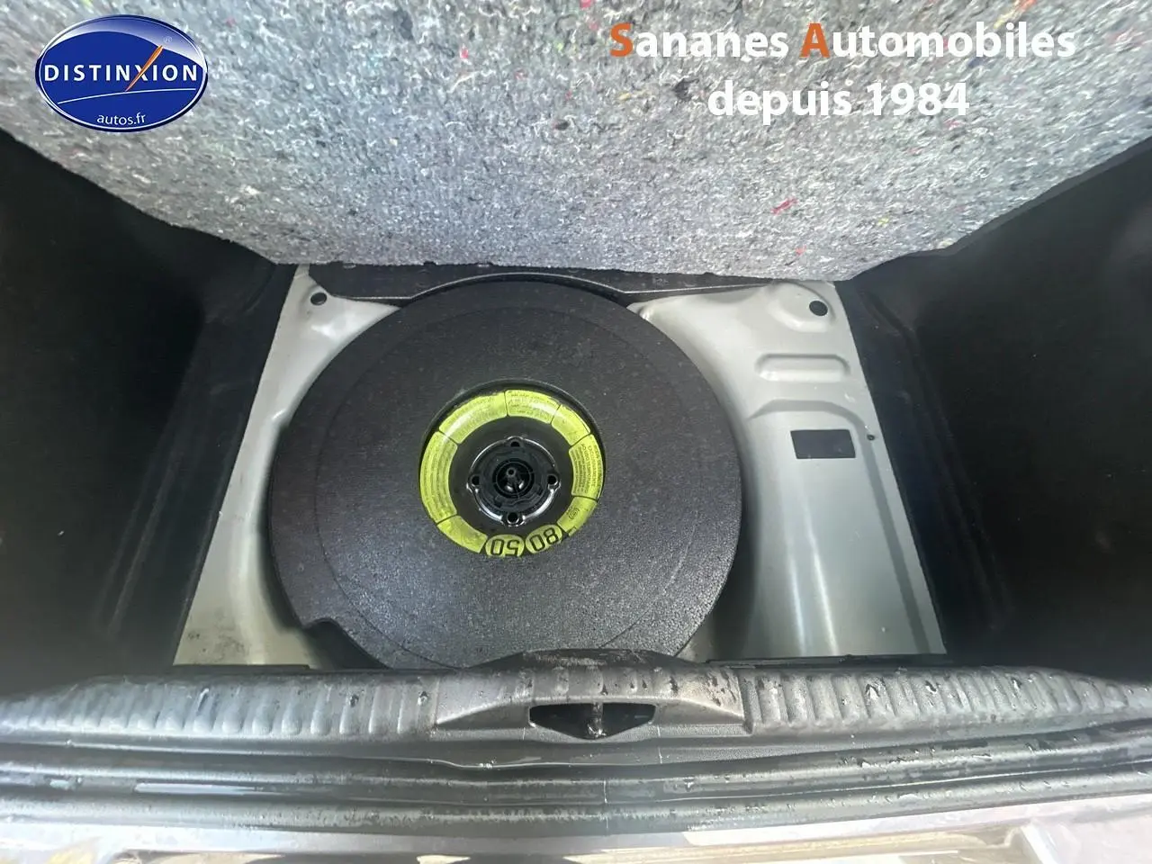 Gros plan sur la roue de secours galette dans le coffre d'une Citroën C3 gris foncé 2023.