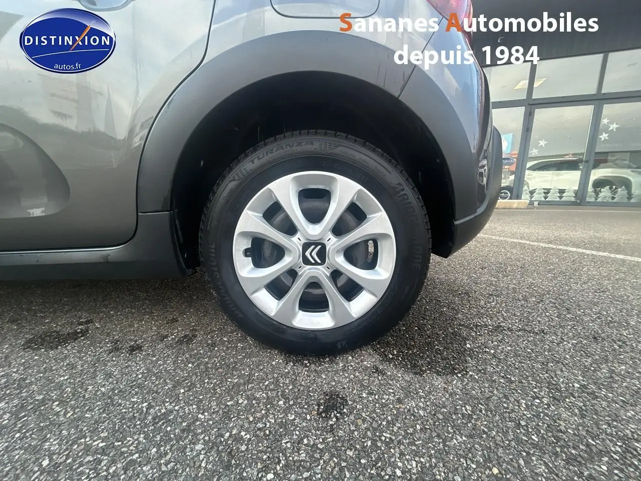 Gros plan sur la roue arrière droite d'une Citroën C3 2023 gris foncé avec jante alliage et logo Citroën central.