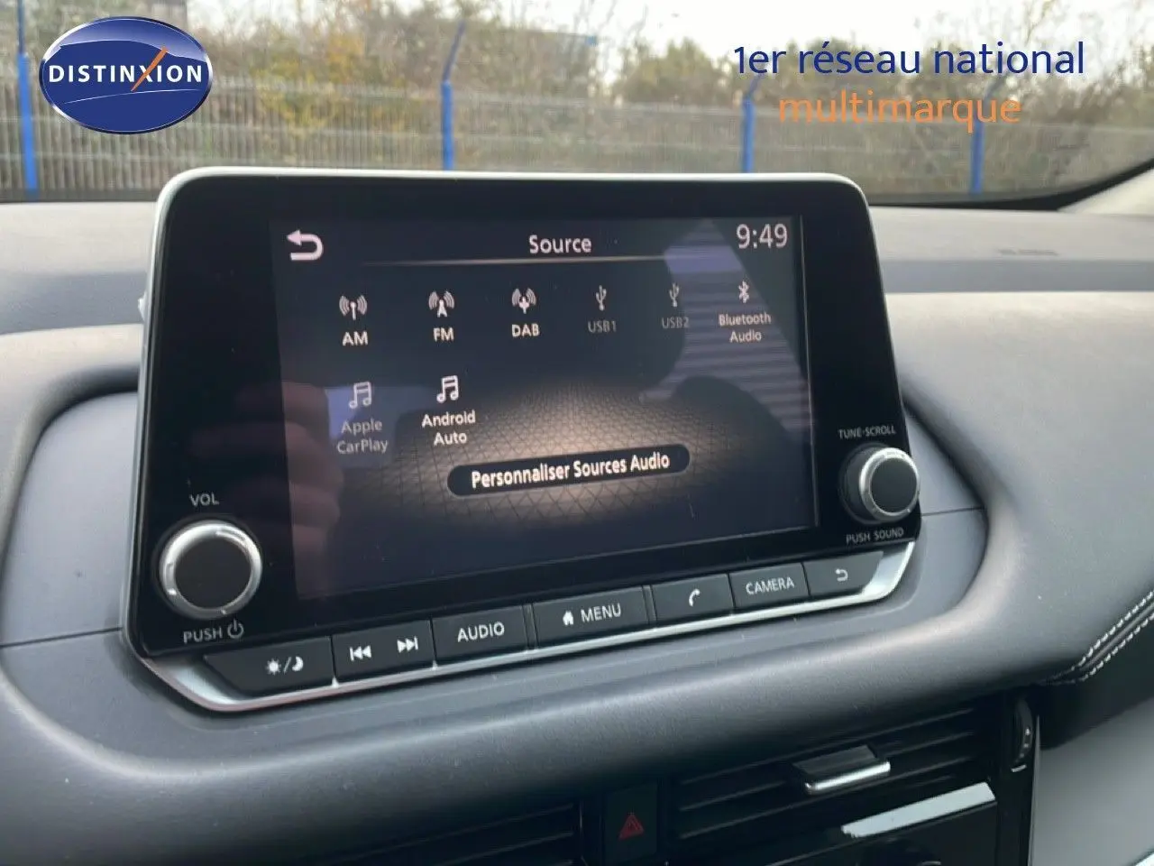 Écran tactile central du Nissan Qashqai 2023 affichant les options audio avec tableau de bord noir et coutures blanches.