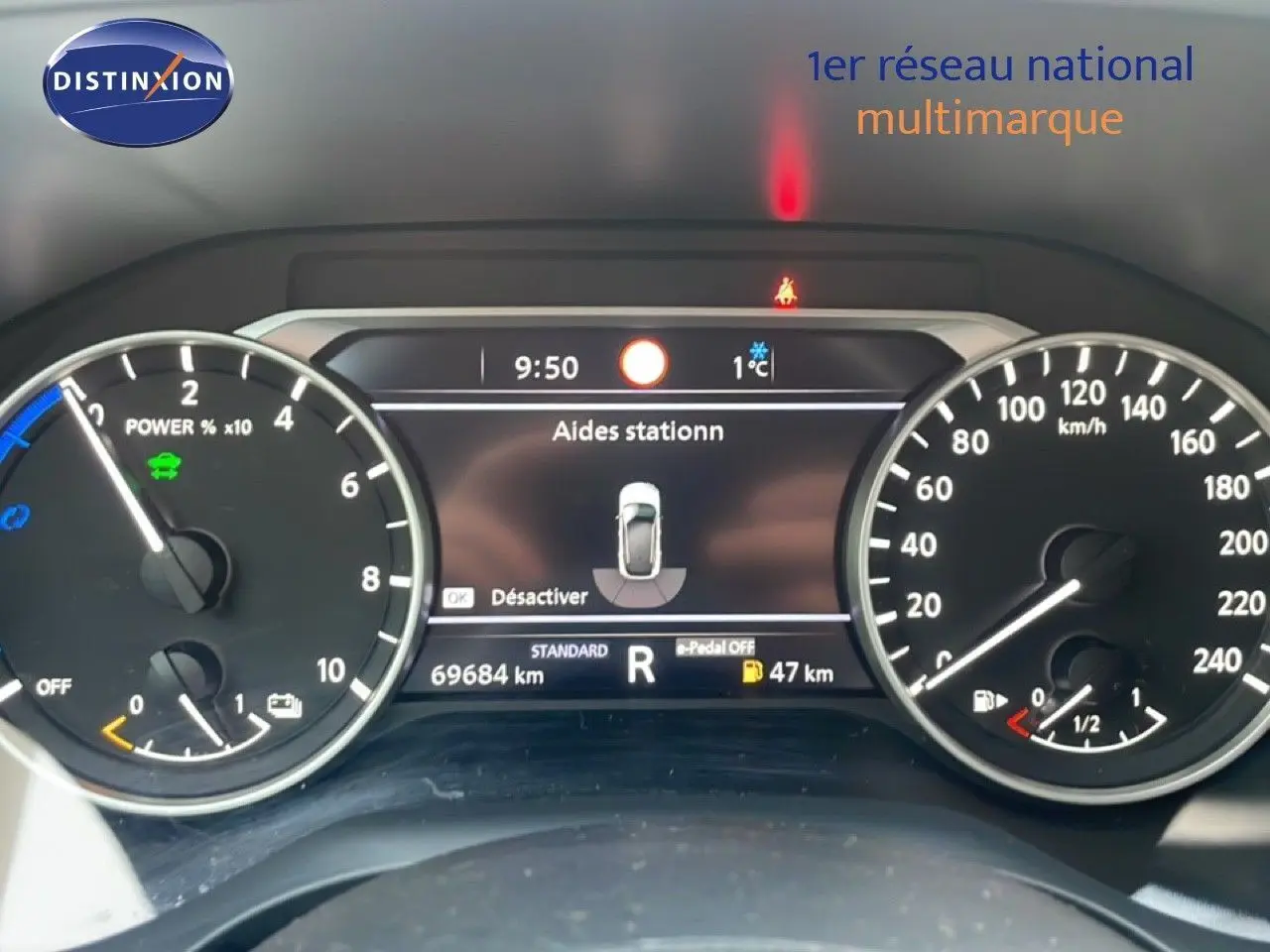 Vue du tableau de bord numérique du Nissan Qashqai 2023 noir métal, affichant l'aide au stationnement et les compteurs.