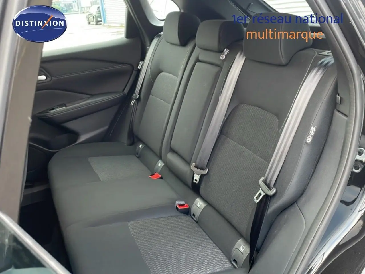 Vue intérieure côté droit des sièges arrière noirs en tissu du Nissan Qashqai 1.5 E-POWER 2023 avec ceintures de sécurité visibles.