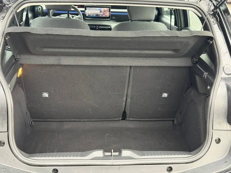 Coffre ouvert vu de l'arrière d'une Citroën C3 1.2 Turbo 100ch PLUS 2025 noir Perla Nera, intérieur noir et banquette rabattue.