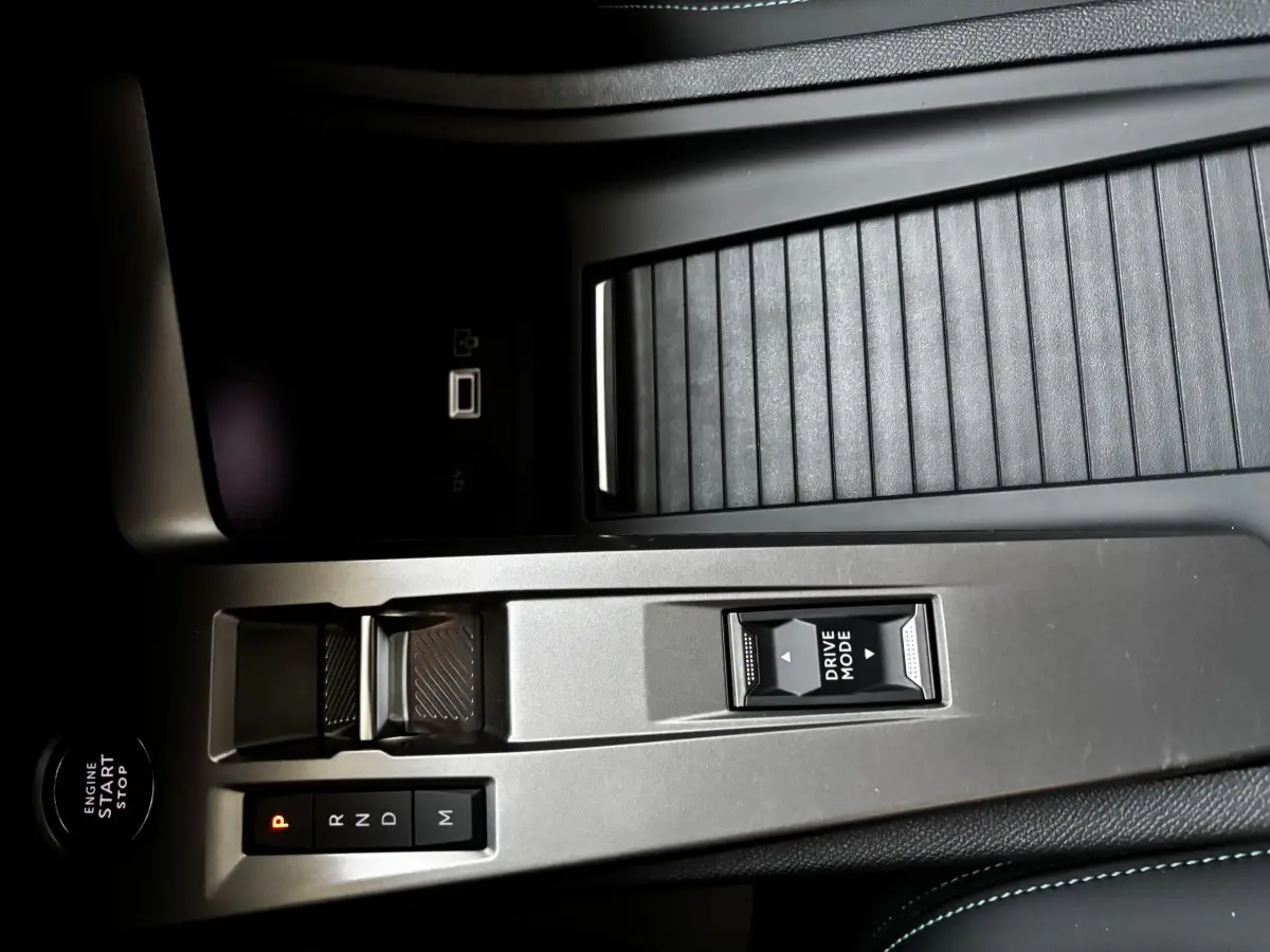 Vue rapprochée de la console centrale de la Peugeot 308 Hybrid 136 e-DCS6 Allure 2025, avec commandes boîte auto et bouton Drive Mode.