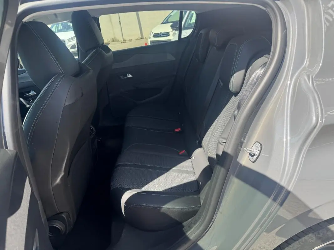 Vue intérieure côté droit sur les sièges arrière noirs d'une Peugeot 308 Hybrid gris 2025, avec porte ouverte.