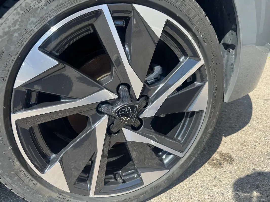 Gros plan sur la jante alliage 17 pouces noire et argentée d'une Peugeot 308 Hybrid gris 2025.
