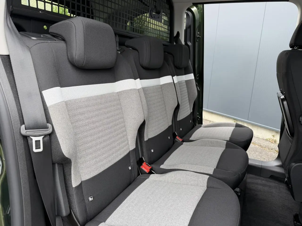 Vue latérale intérieure des trois sièges arrière gris clair et noir du Citroën Berlingo Multispace Vert Sirkka avec porte coulissante ouverte.