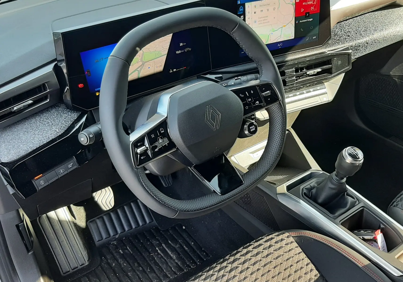 Vue intérieure du poste de conduite de la Renault Clio VI TCe 115ch Techno, volant multifonctions et écran large numérique.