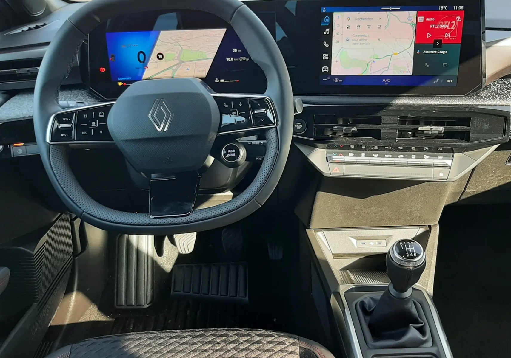 Vue intérieure de la Renault Clio VI TCe 115ch Techno 2026, tableau de bord numérique et levier de vitesse manuel visibles.