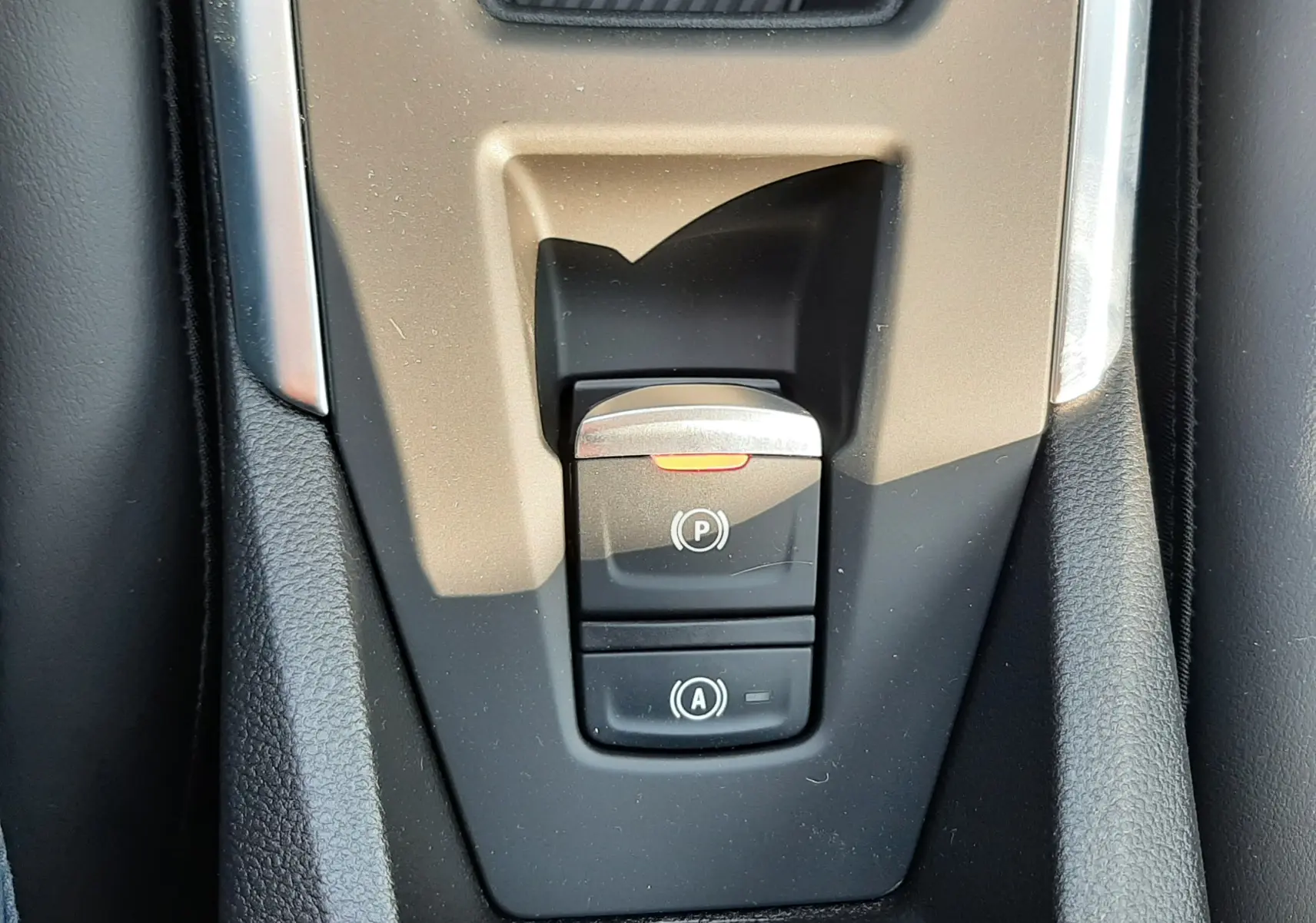 Gros plan sur la console centrale noire et grise de la Renault Clio VI TCe 115ch Techno, montrant les commandes du frein à main électrique et de l’arrêt automatique.