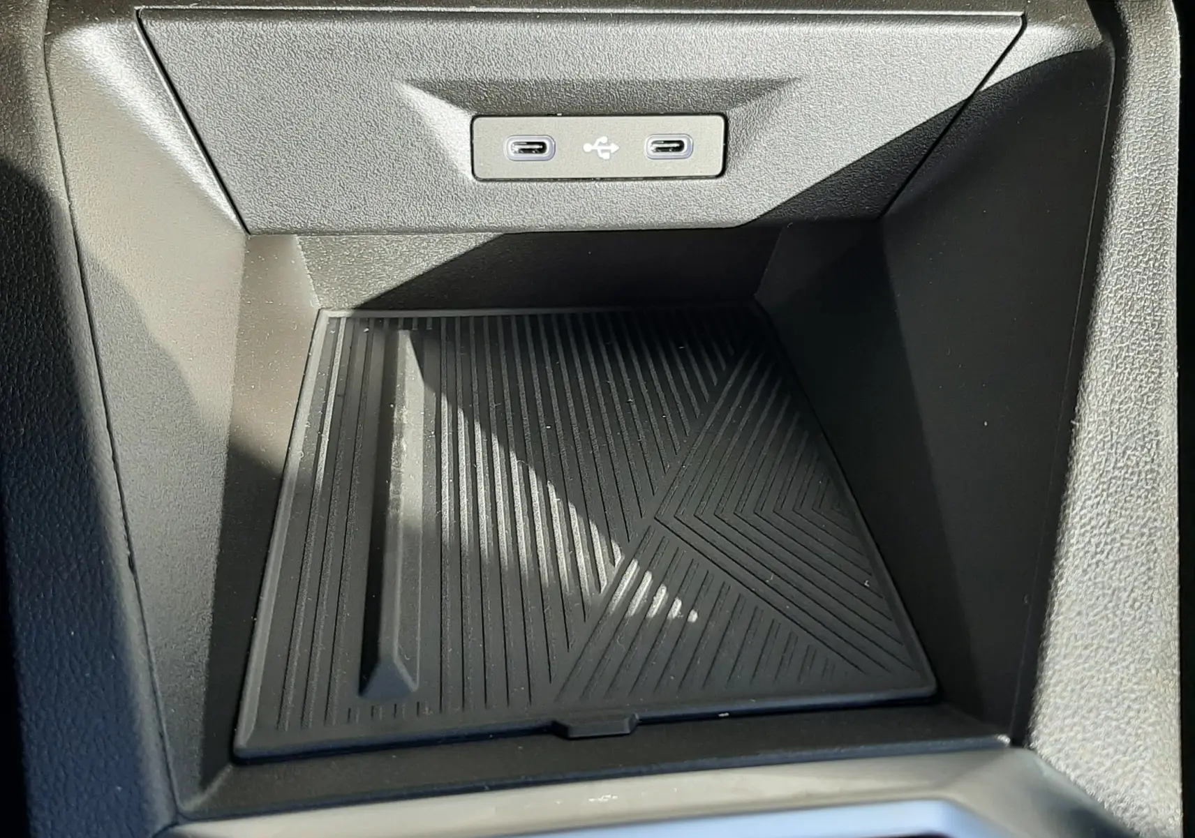Gros plan sur la console centrale de la Renault Clio VI TCe 115ch Techno avec deux ports USB-C intégrés et un espace de rangement noir.